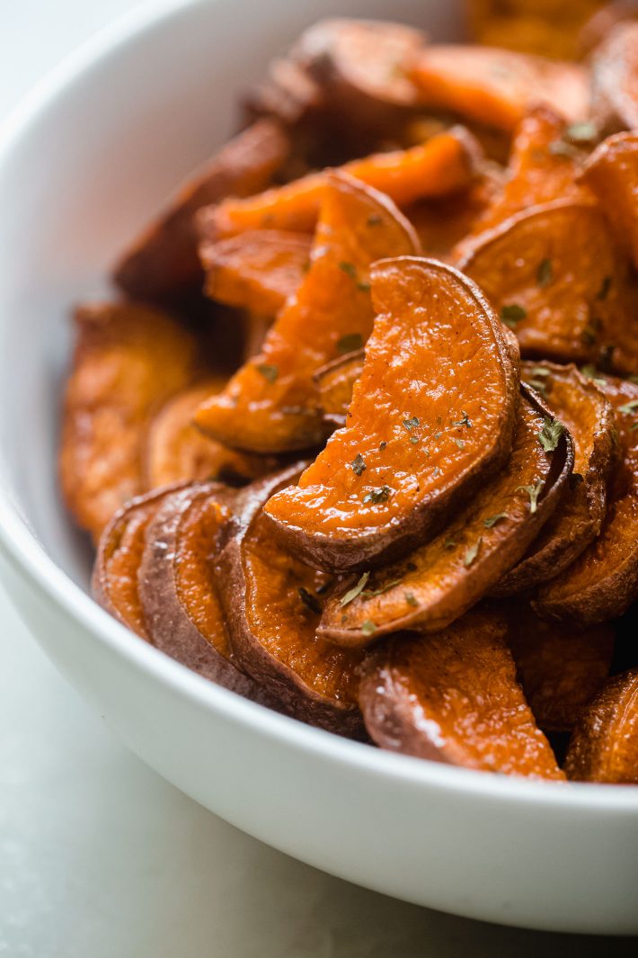 roasted sweet potato half moons in white bowls with parsley