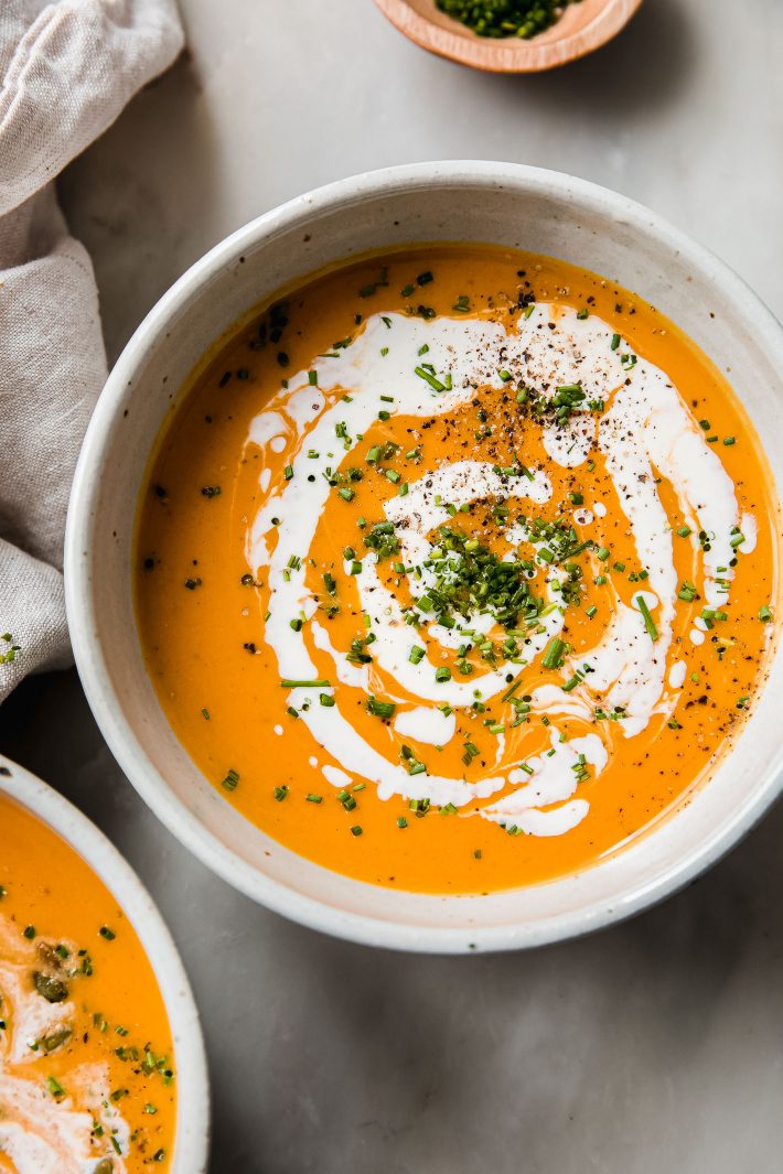 Honeynut squash soup in bowl topped with cream and chives