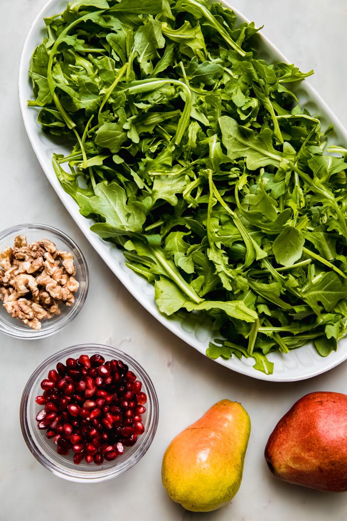 arugula in platter with walnuts pomegranate and pears on the side