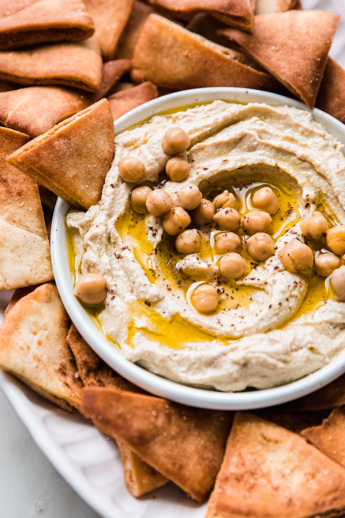 hummus with pita chip resting in bowl with chickpeas 