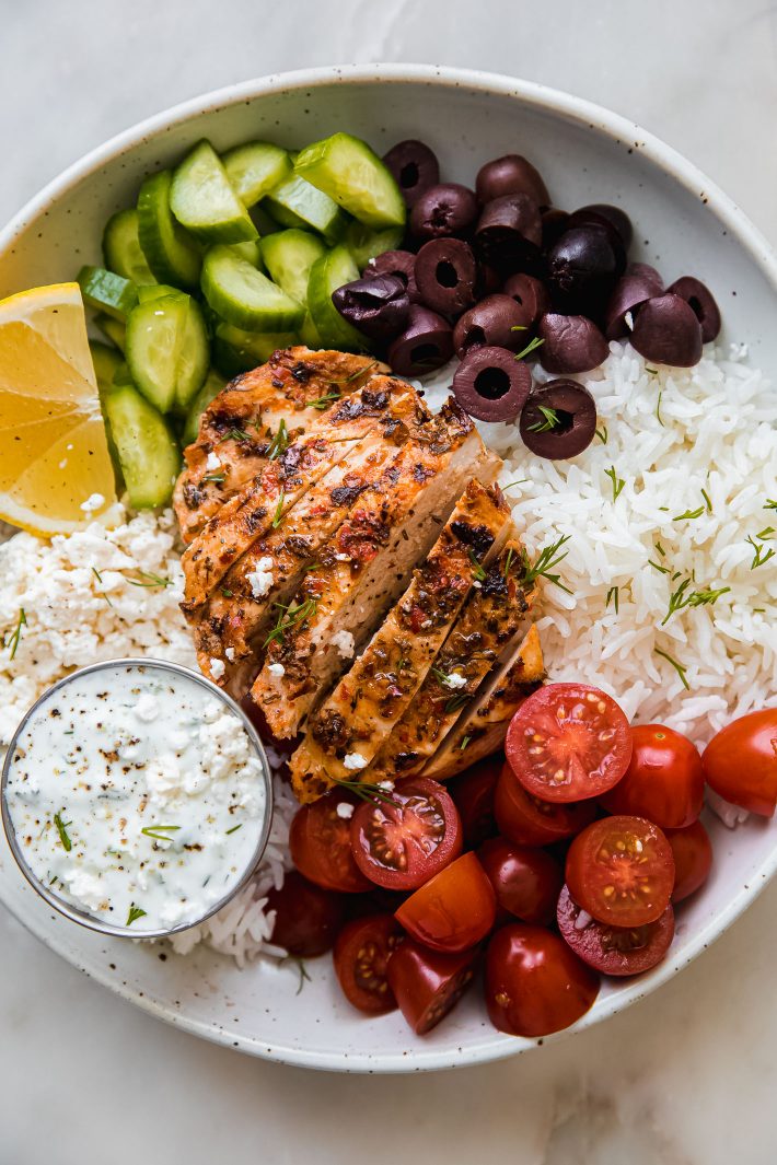 chicken tzatziki bowls with lemon wedges on white marble 