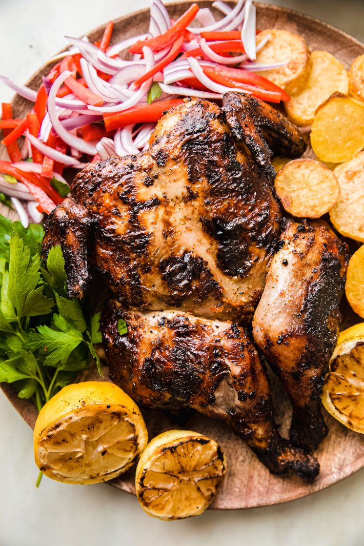 peri peri chicken in wood board with potatoes and onion salad