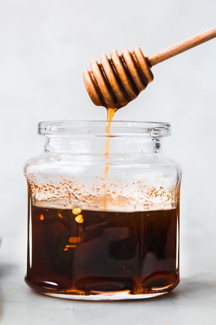 Hot honey dripping into jar from honeycomb