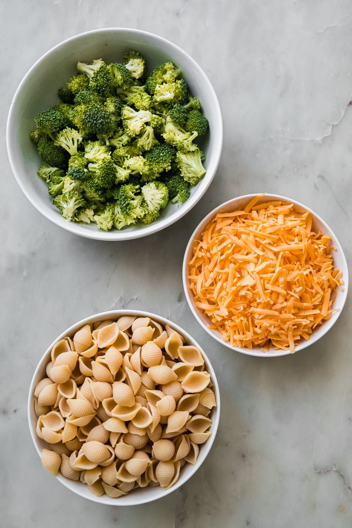 broccoli, cheese, and shells in separate bowls