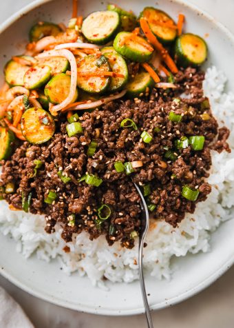 gochujang beef in bowl with fork and cucumber salad