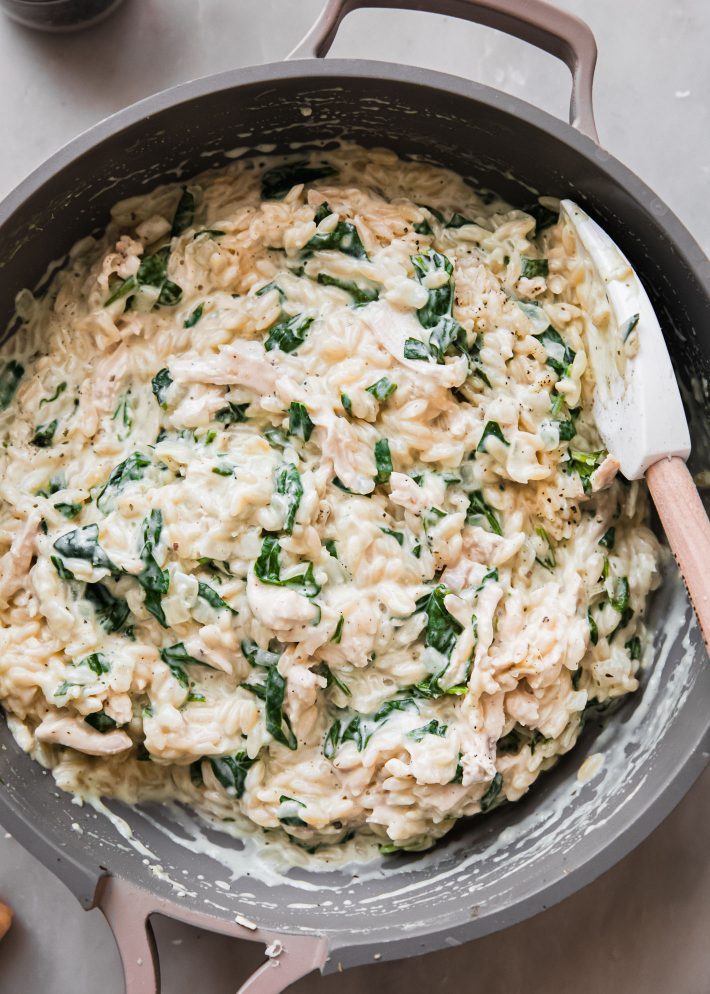 creamy orzo with spatula in pan