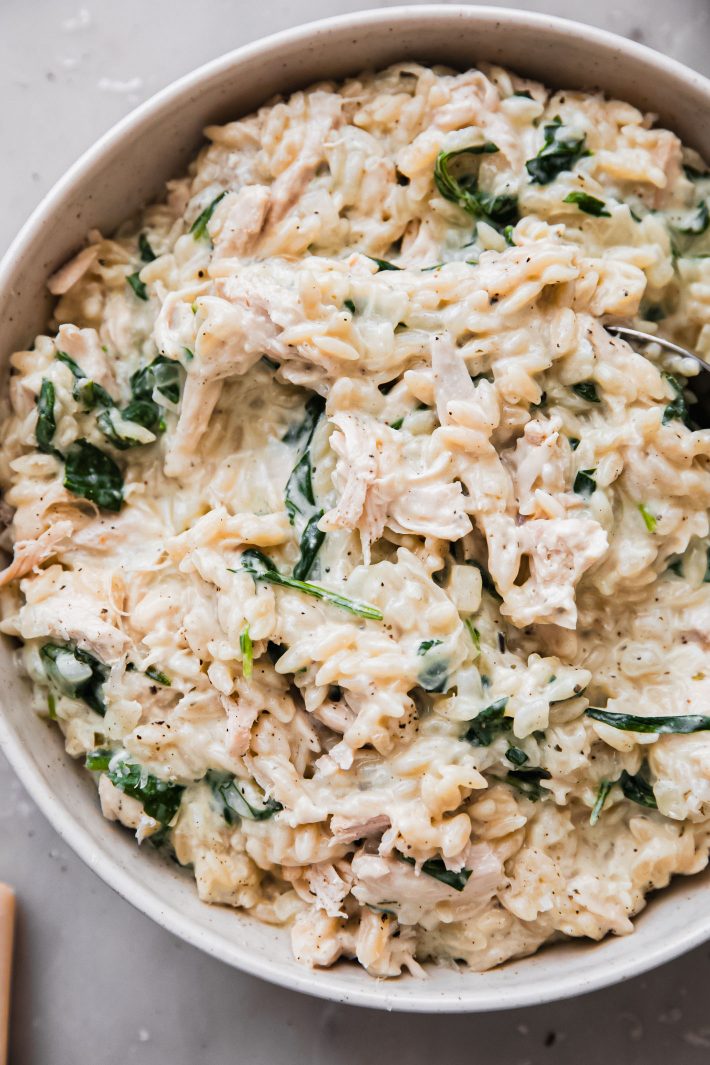 orzo with boursin cream sauce, baby spinach and chicken in bowl