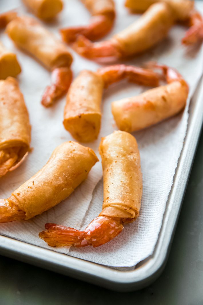 cooked shrimp rolls on paper towel-lined sheet pan.