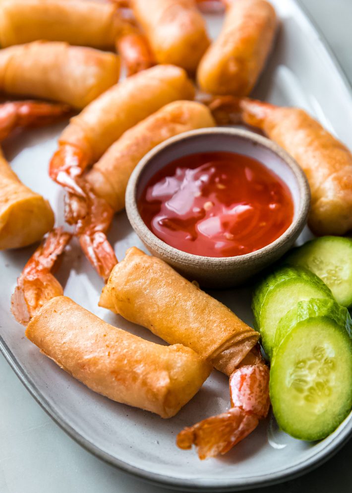 shrimp in a blanket on plate with cucumbers and sauce
