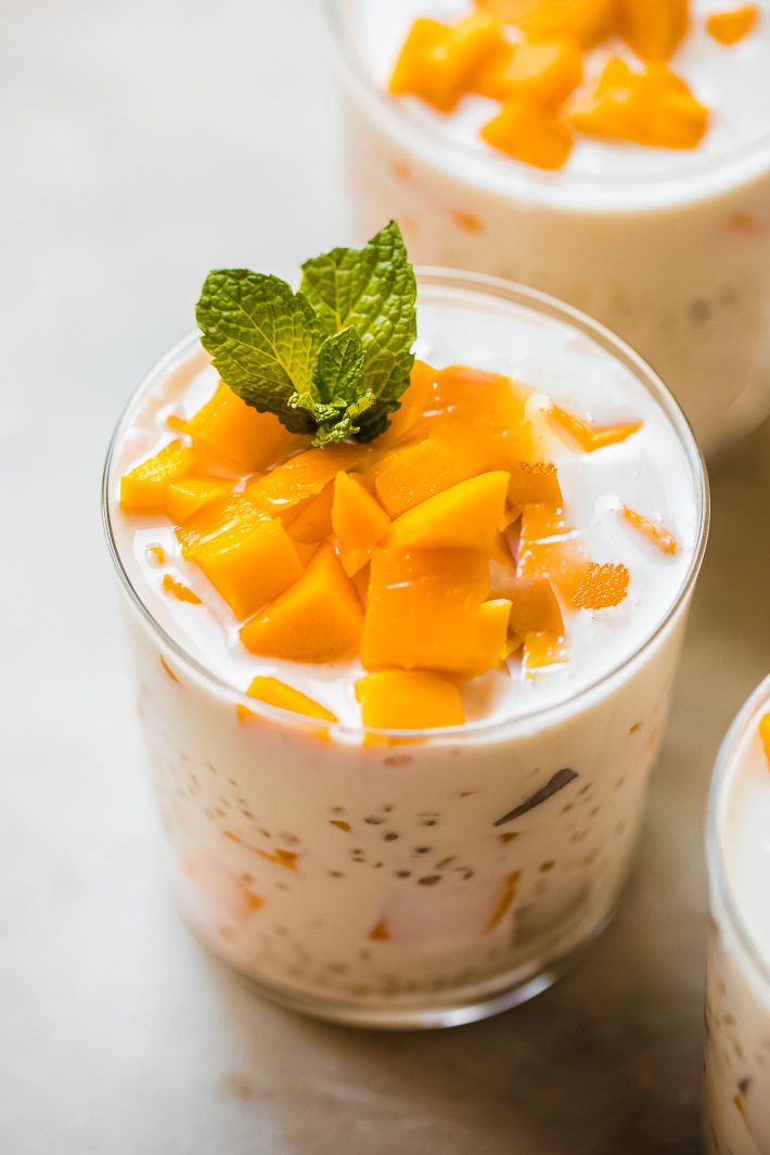 mango sago dessert in cup topped with mango chunks and a sprig of mint